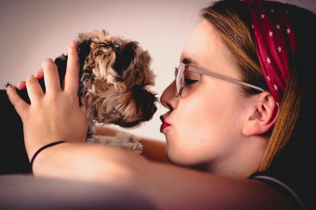 girl kissing small dog